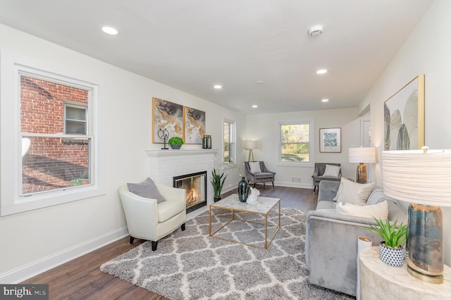 living room featuring dark wood-type flooring and a brick fireplace