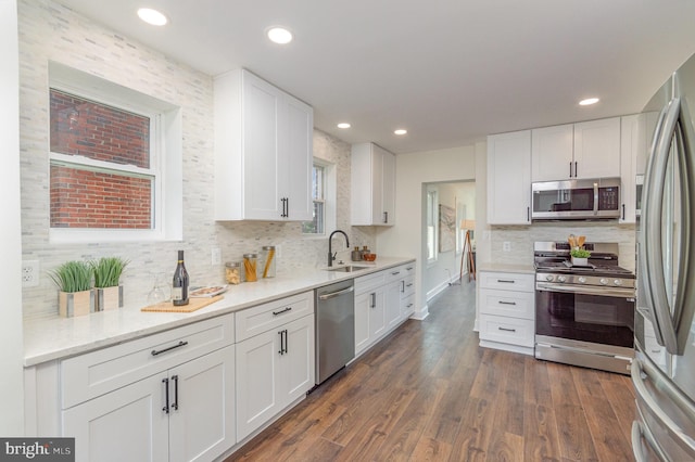 kitchen with white cabinets, stainless steel appliances, sink, and dark hardwood / wood-style floors