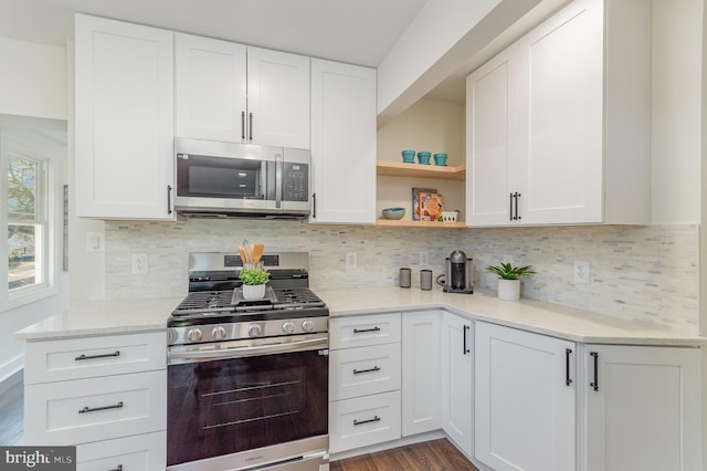 kitchen with backsplash, appliances with stainless steel finishes, hardwood / wood-style flooring, and white cabinets