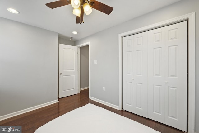 bedroom with ceiling fan, dark wood-type flooring, and a closet