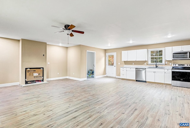 kitchen with sink, light hardwood / wood-style flooring, ceiling fan, appliances with stainless steel finishes, and white cabinetry