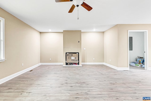 unfurnished living room with electric panel, ceiling fan, and light wood-type flooring