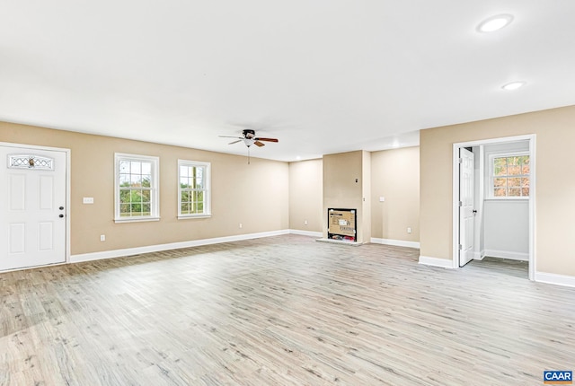 unfurnished living room with ceiling fan, a healthy amount of sunlight, and light wood-type flooring