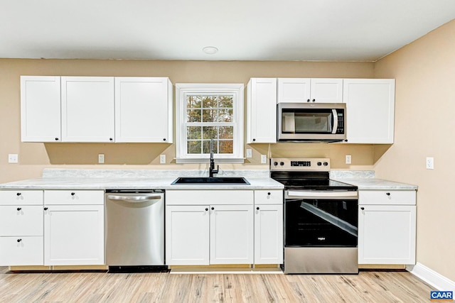 kitchen with white cabinetry, sink, stainless steel appliances, and light wood-type flooring