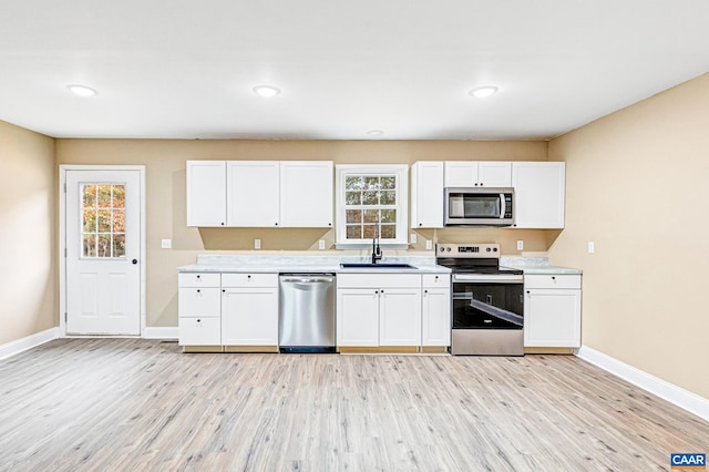 kitchen with a wealth of natural light, sink, stainless steel appliances, and light hardwood / wood-style floors