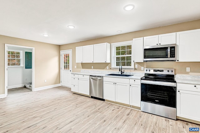 kitchen featuring appliances with stainless steel finishes, light wood-type flooring, white cabinetry, and sink