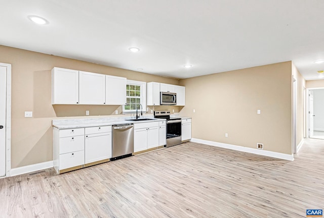 kitchen featuring sink, white cabinets, stainless steel appliances, and light wood-type flooring