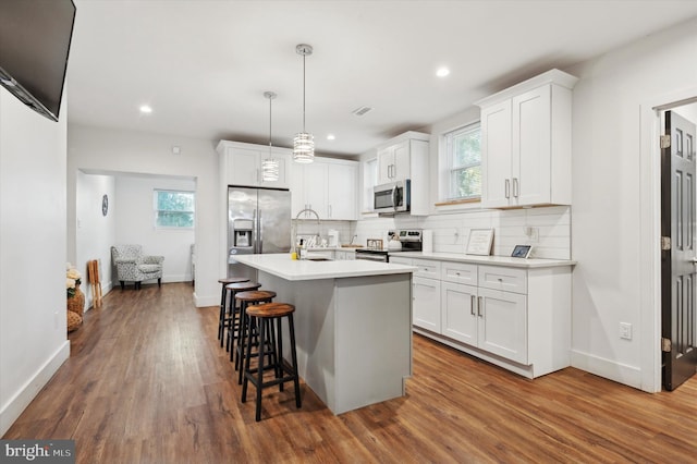 kitchen featuring white cabinets, decorative light fixtures, dark hardwood / wood-style flooring, and stainless steel appliances