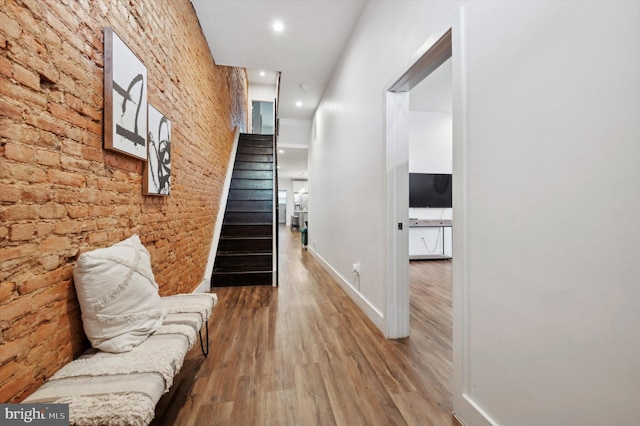 hall featuring hardwood / wood-style floors and brick wall