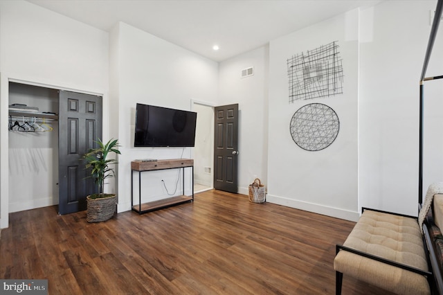 living room with a high ceiling and dark wood-type flooring