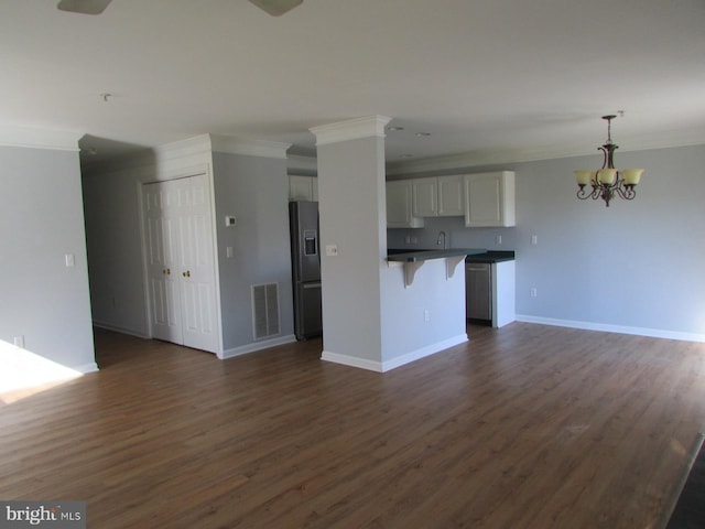 kitchen featuring hanging light fixtures, a breakfast bar area, ornamental molding, dark hardwood / wood-style floors, and stainless steel fridge