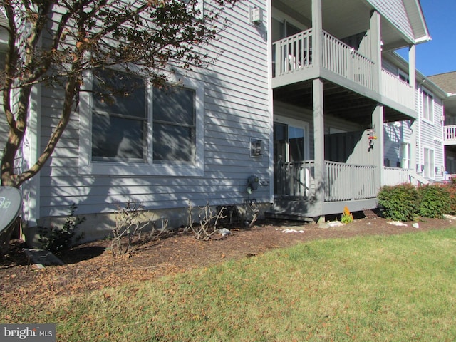 view of side of home featuring a yard and a balcony