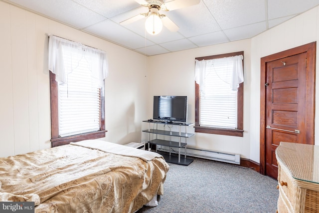 bedroom featuring a drop ceiling, carpet flooring, baseboard heating, and ceiling fan