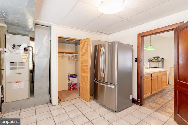 kitchen with pendant lighting, light tile patterned floors, and stainless steel refrigerator