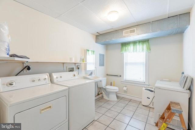 washroom featuring electric panel, light tile patterned flooring, and washing machine and clothes dryer