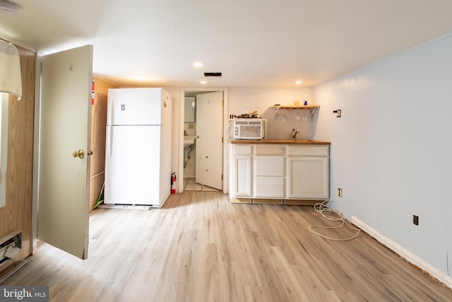 kitchen featuring light wood-type flooring, a baseboard radiator, and white refrigerator