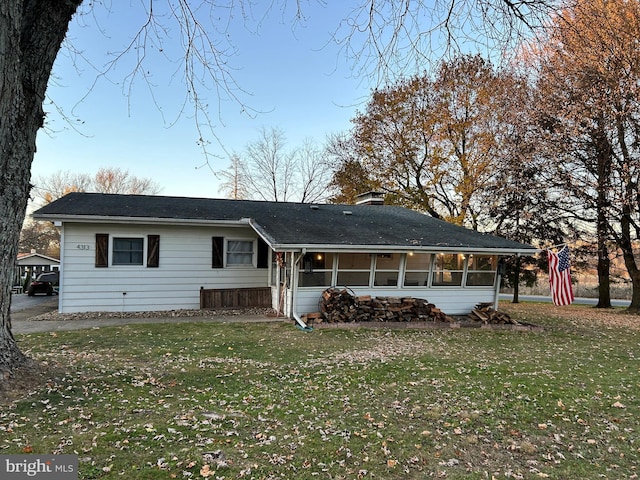 back of property with a lawn and a sunroom