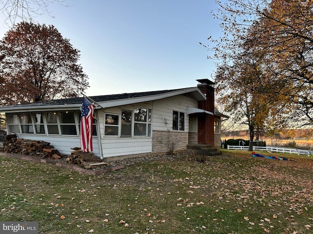 view of front of house with a sunroom and a lawn