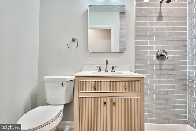 bathroom featuring vanity, toilet, and a tile shower