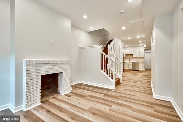 unfurnished living room with a brick fireplace and light hardwood / wood-style flooring