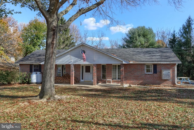 ranch-style home featuring covered porch and a front yard