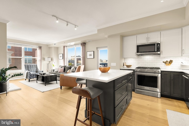 kitchen with white cabinets, a breakfast bar area, light wood-type flooring, a kitchen island, and stainless steel appliances