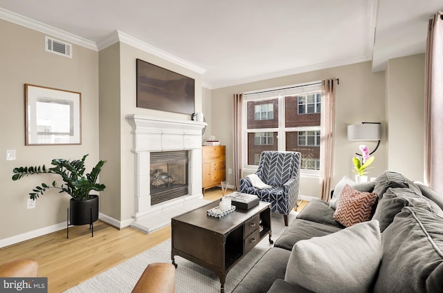 living room with hardwood / wood-style flooring, crown molding, and a fireplace