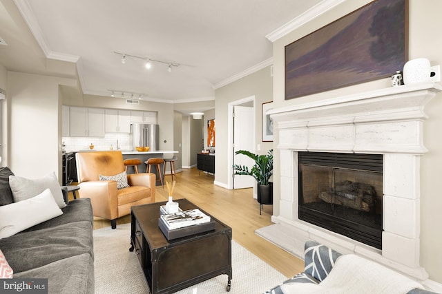 living room with light hardwood / wood-style floors, crown molding, and rail lighting