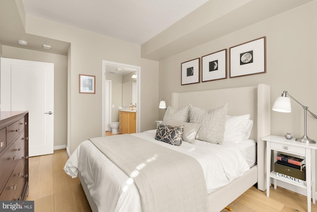 bedroom featuring light hardwood / wood-style floors and ensuite bath