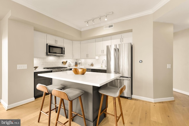 kitchen with white cabinetry, a center island, sink, stainless steel appliances, and a kitchen bar