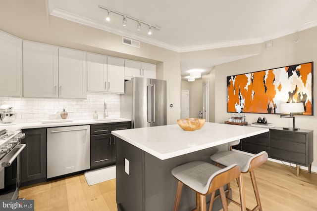 kitchen featuring a center island, high quality appliances, light hardwood / wood-style flooring, decorative backsplash, and white cabinetry