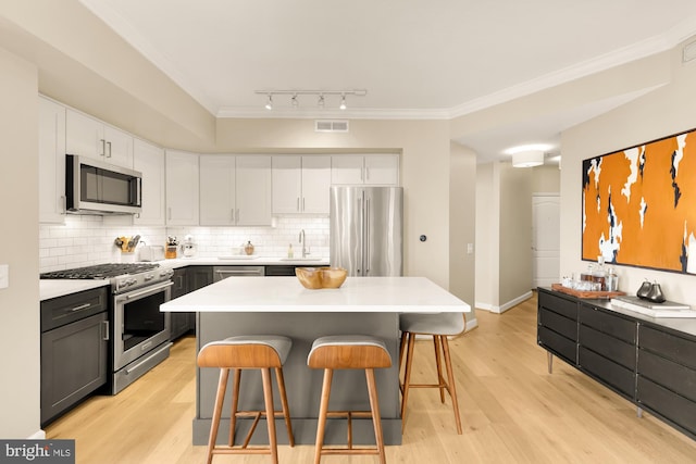 kitchen featuring a breakfast bar, backsplash, premium appliances, a kitchen island, and white cabinetry