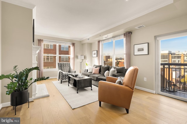 living room with light hardwood / wood-style floors, crown molding, and a healthy amount of sunlight