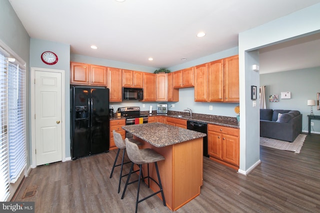 kitchen featuring a center island, sink, dark hardwood / wood-style floors, a breakfast bar, and black appliances