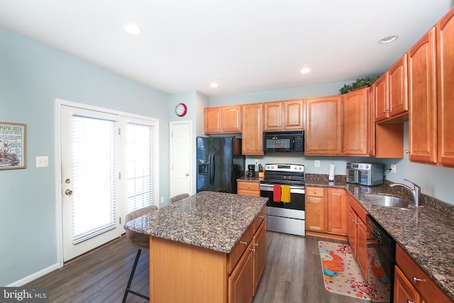 kitchen with a wealth of natural light, sink, a center island, and black appliances