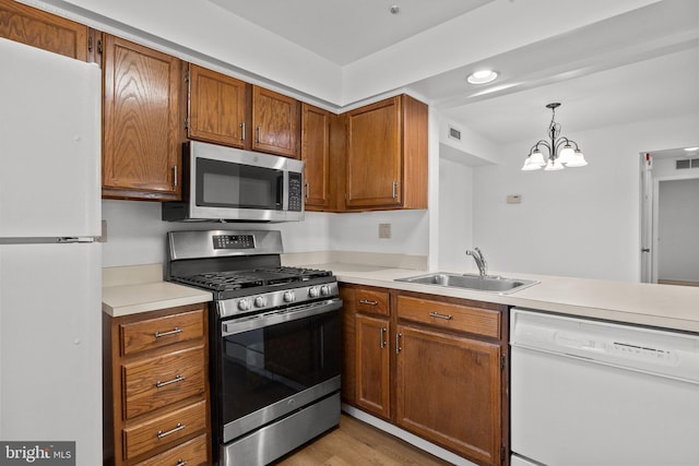 kitchen featuring stainless steel appliances, sink, a chandelier, light hardwood / wood-style flooring, and pendant lighting