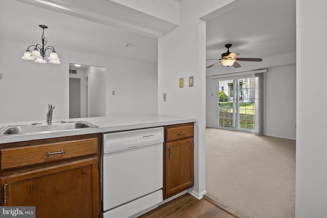 kitchen with white dishwasher, pendant lighting, sink, light colored carpet, and ceiling fan with notable chandelier