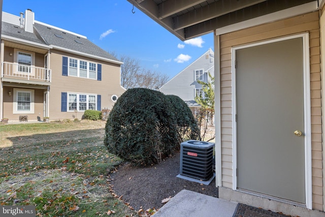 exterior space with central AC unit, a balcony, and a yard