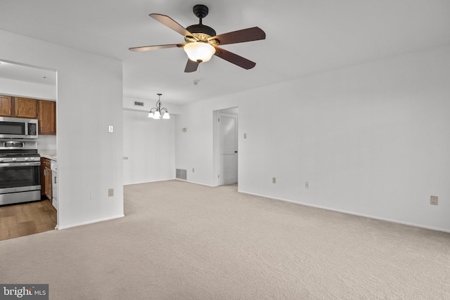 unfurnished living room featuring light carpet and ceiling fan with notable chandelier