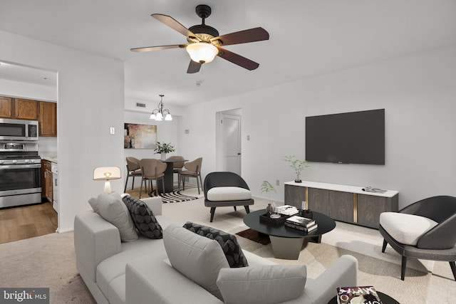 living room featuring light wood-type flooring and ceiling fan with notable chandelier