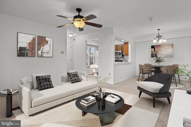 carpeted living room featuring ceiling fan with notable chandelier