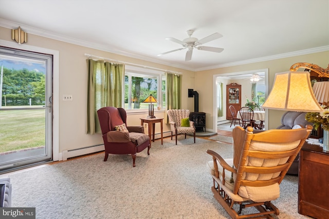 sitting room featuring a wood stove, baseboard heating, a healthy amount of sunlight, and crown molding