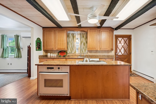 kitchen featuring a kitchen island, light wood-type flooring, oven, and a baseboard radiator