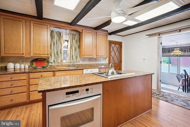 kitchen featuring beamed ceiling, sink, an island with sink, and light hardwood / wood-style flooring