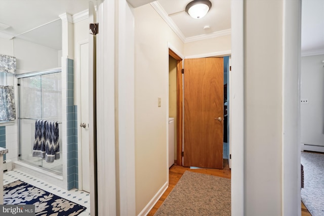 hallway with baseboard heating, light wood-type flooring, and ornamental molding