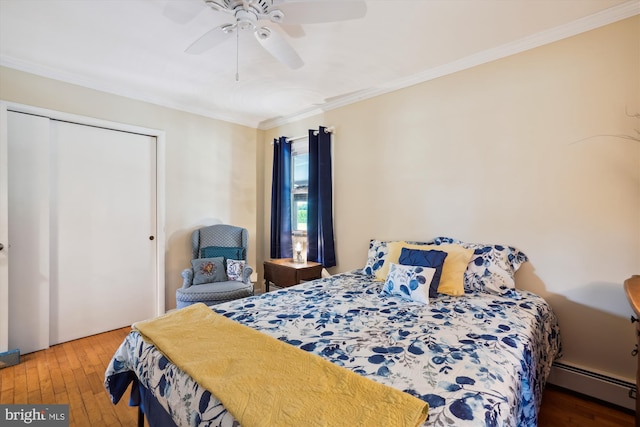 bedroom with a closet, crown molding, hardwood / wood-style flooring, baseboard heating, and ceiling fan