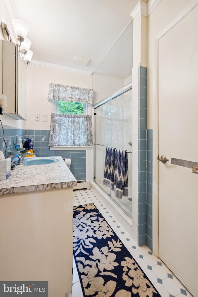 bathroom with a baseboard heating unit, tile walls, ornamental molding, an enclosed shower, and vanity