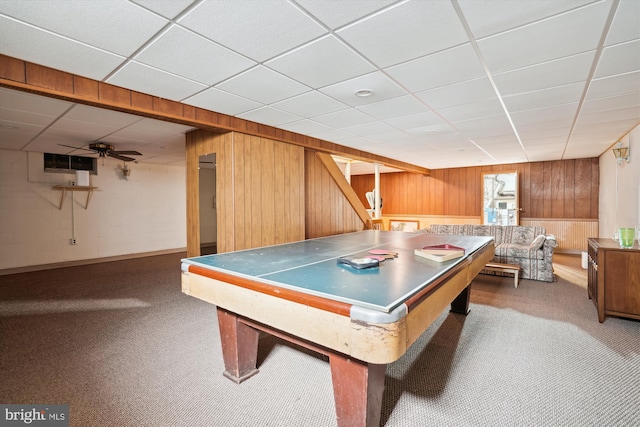 recreation room featuring a paneled ceiling, carpet flooring, and wooden walls