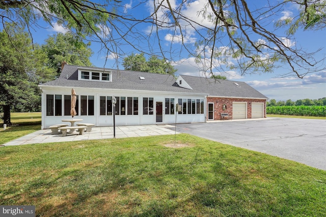 back of property featuring a garage, a sunroom, and a yard