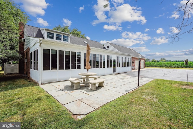 rear view of house featuring a patio, a sunroom, and a yard